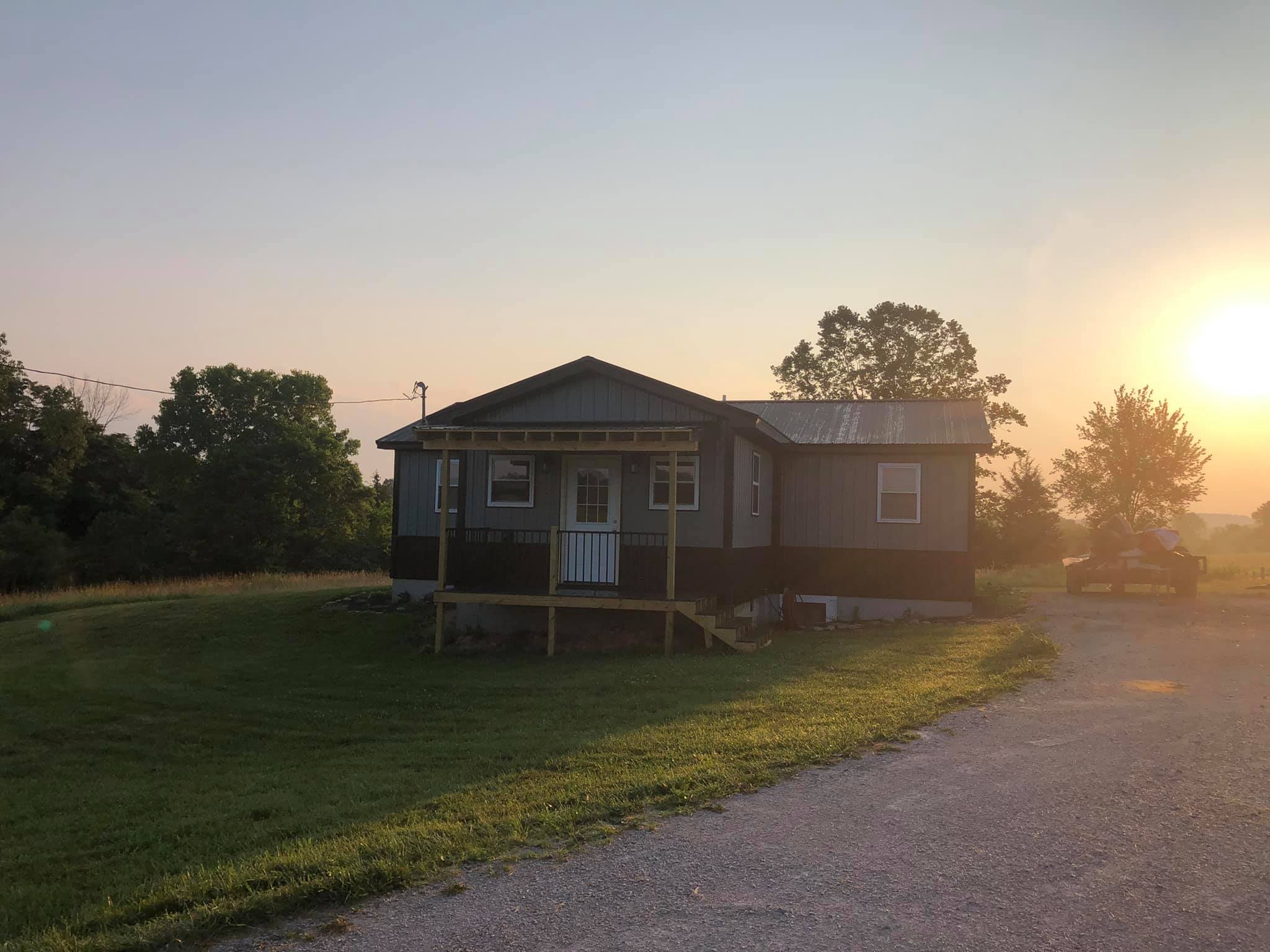 Rustic lodge on a grassy knoll at sunrise.