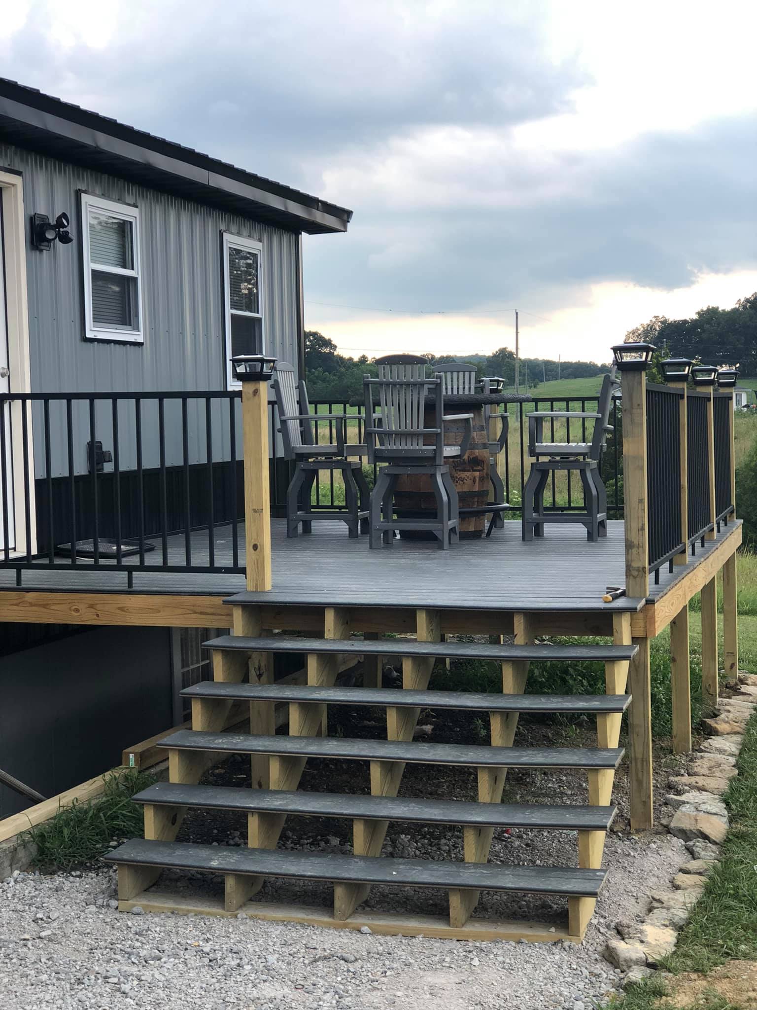 Deck of a hunting lodge with seating and a barrel table.
