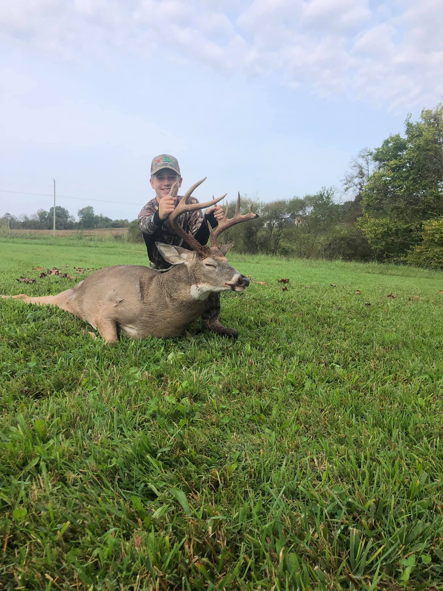 Young hunter proudly displays a large buck with velvet antlers raised.