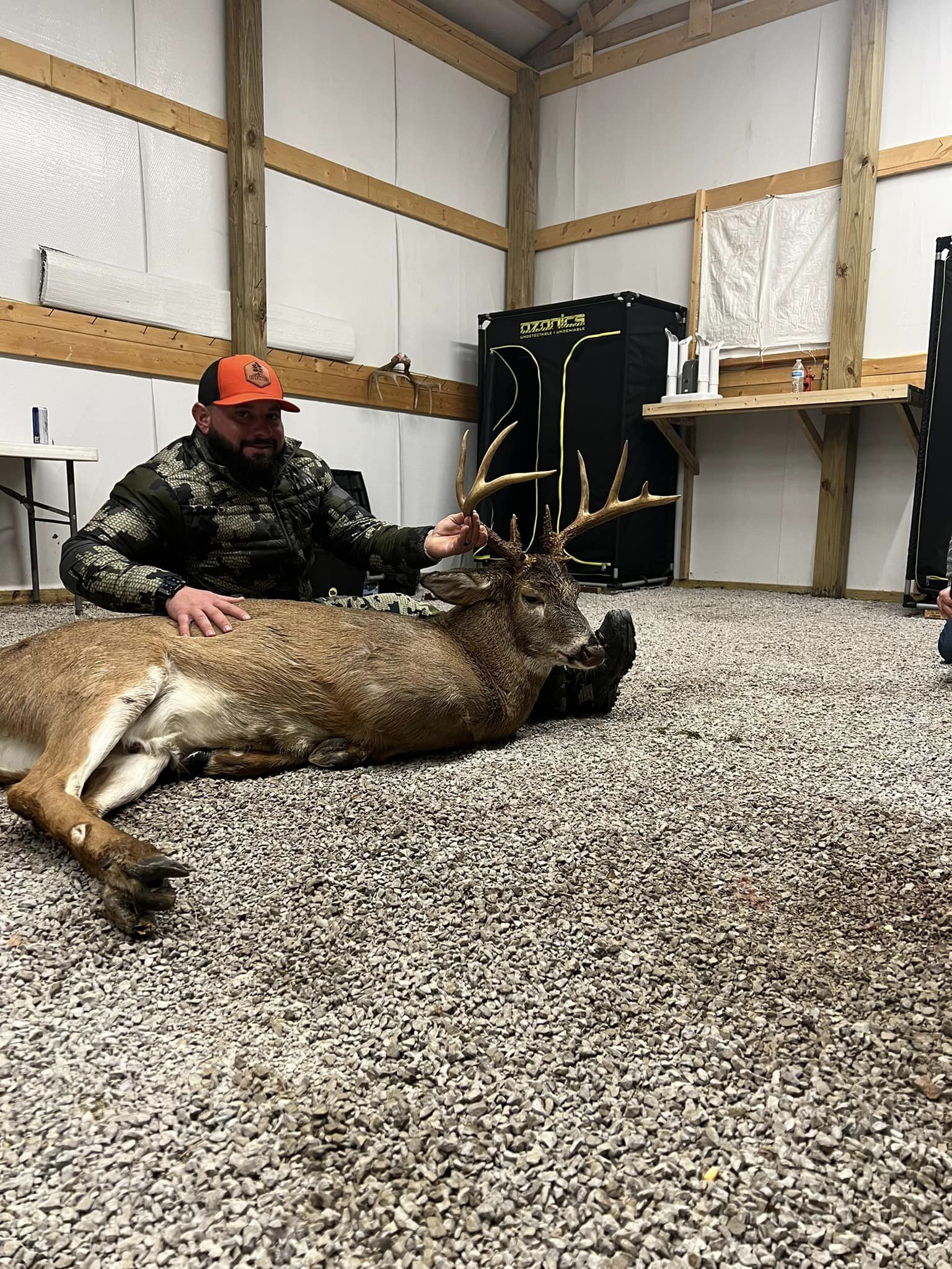Hunter with a large-antlered buck inside a barn.