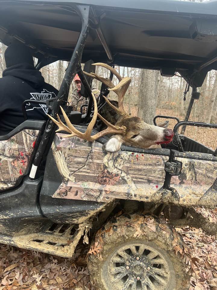 A hunter transports a large buck in a muddy side-by-side in Kentucky.