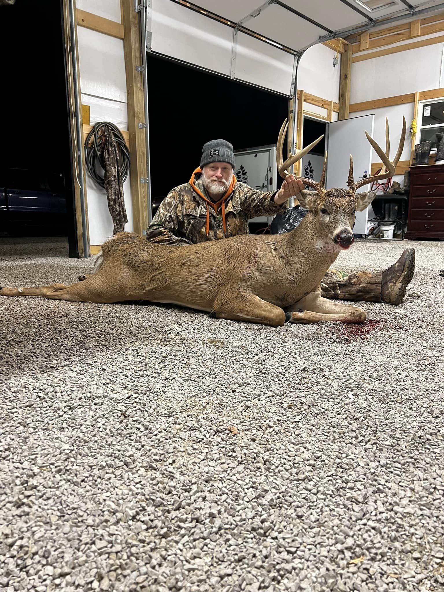 Hunter and a large buck with impressive antlers resting on gravel