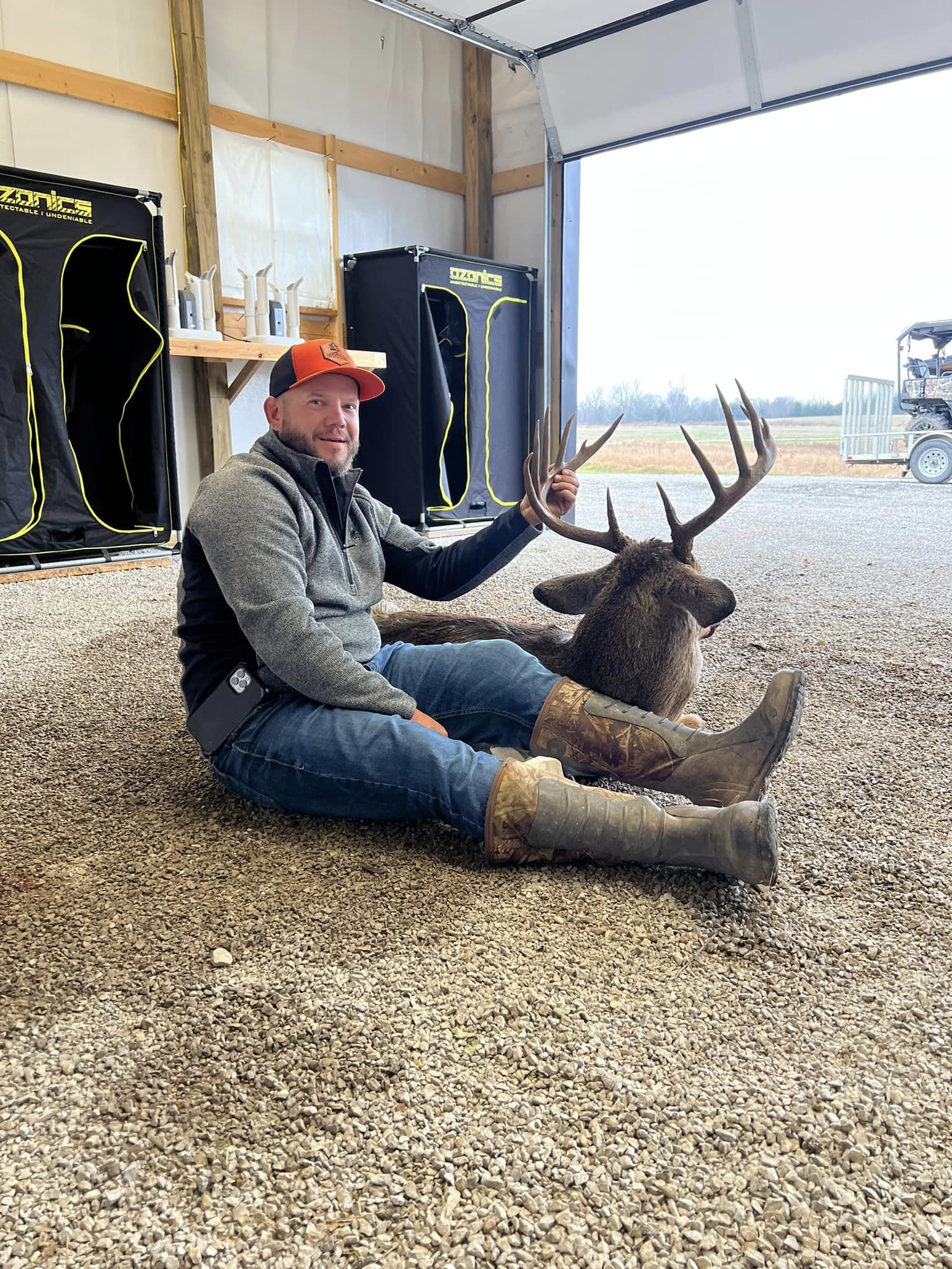 Hunter sits with a large buck inside a hunting lodge.