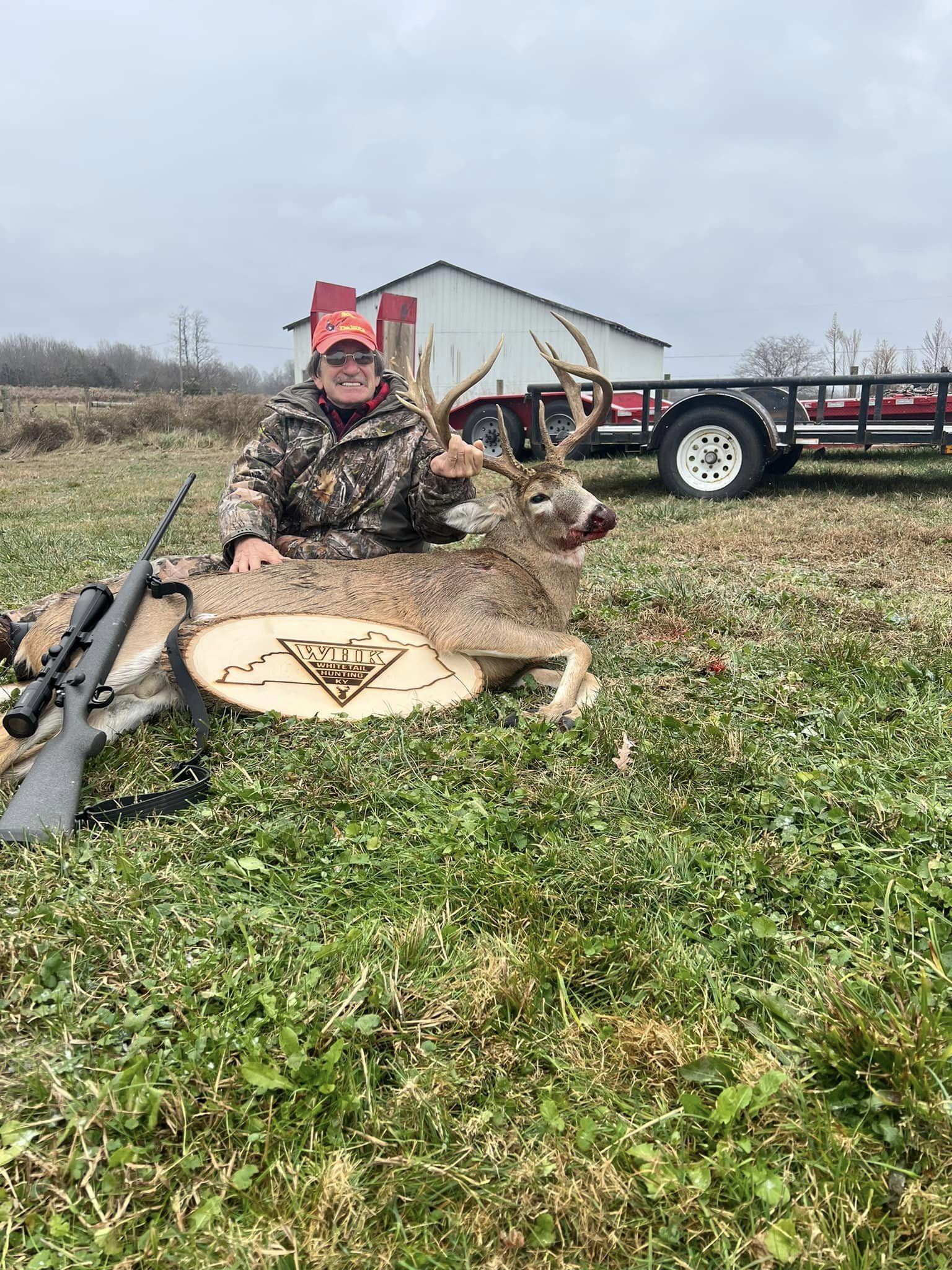 Hunter with a whitetail buck wearing 'Whitetail Hunting Kentucky' logo.